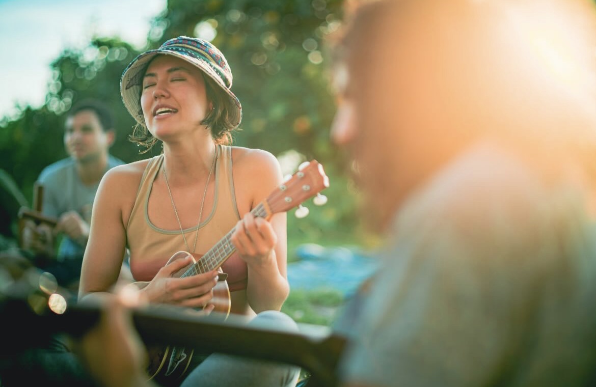 Angela playing ukulele outdoors at golden hour — retreat vibes